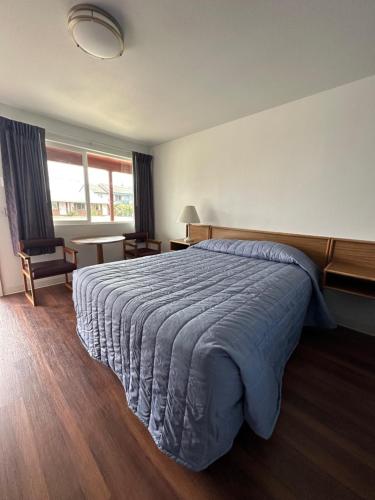 a bedroom with a large bed with a blue blanket at Captain John's Motel in Charleston