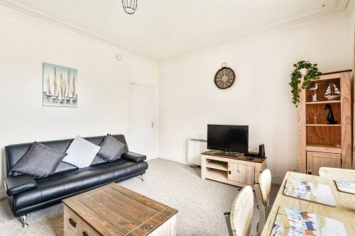uma sala de estar com um sofá de couro preto e uma mesa em Tiny home at Dundee em Dundee