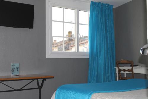 a bedroom with a blue curtain and a window at Les Colonnes in Saint-Martin-de-Ré