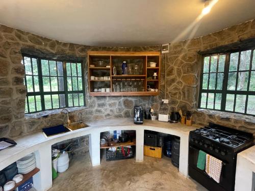 a kitchen with stone walls and a counter top at Double Tent - Dolly Farm & River Camp in Usa River