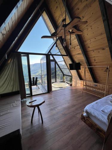 sypialnia z łóżkiem i stołem oraz dużym oknem w obiekcie Nirvana dağ evleri w mieście Çamlıhemşin
