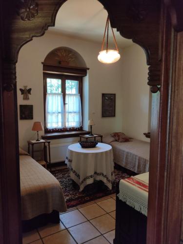 een kamer met 2 bedden, een tafel en een piano bij White stone house with great sea view in Tsagarada