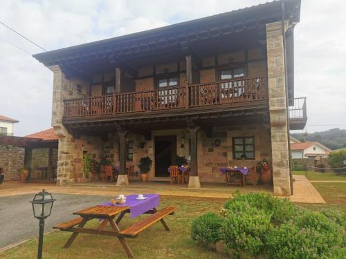 a building with a balcony and a picnic table at Posada La Aldea in Oreña