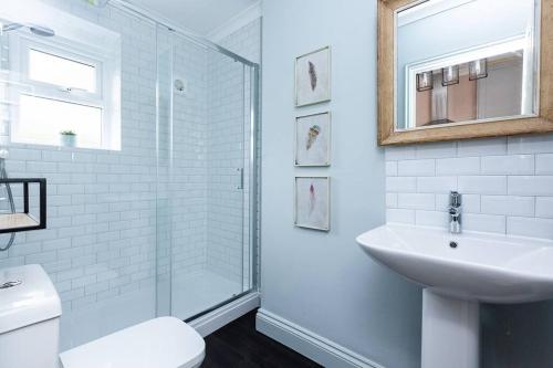 uma casa de banho branca com um lavatório e um chuveiro em Harriet - Quaint one bedroom apartment with easy parking em Kent