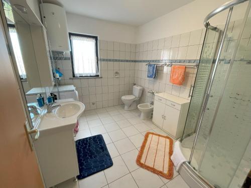 een badkamer met een douche, een wastafel en een toilet bij Villa Rosa Apartman in Loborika