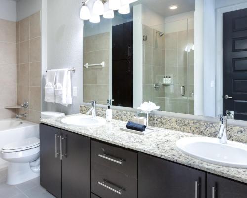 a bathroom with two sinks and a toilet and a mirror at Locale at the Galleria - Houston in Houston