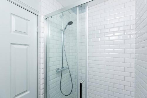 a white bathroom with a shower with a glass door at Queenie - Charming one bedroom apartment in quiet location in Kent