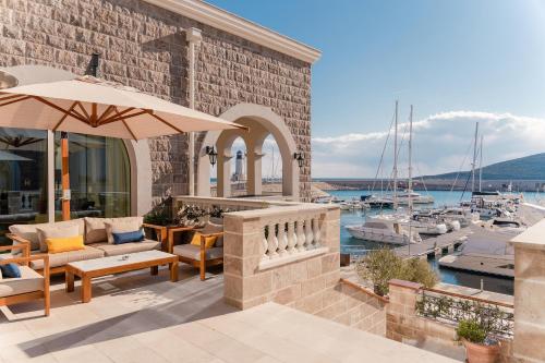 un patio con sillas, una sombrilla y un puerto deportivo en The Chedi Luštica Bay, en Tivat