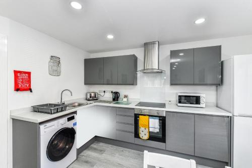 a kitchen with a washing machine and a microwave at Woodstock House - A Spacious Apartment Block with 9 Two-Bedroom Flats in Hucknall