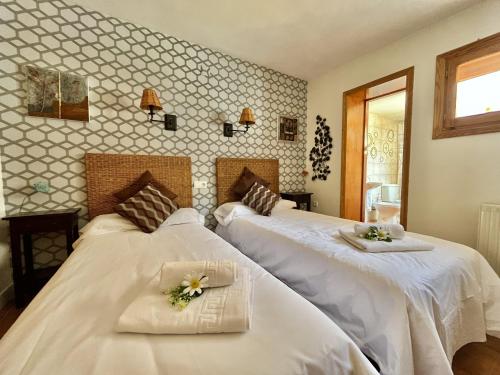 Dos camas en una habitación de hotel con flores. en Hostal - Restaurante Nomadas by Gloove, en Villalba de la Sierra