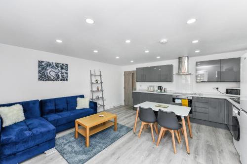 sala de estar con sofá azul, mesa y sillas en Woodstock House - A Spacious Apartment Block with 9 Two-Bedroom Flats, en Hucknall