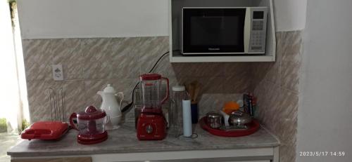 a kitchen counter with a microwave and red appliances at Casa no Centro Bananeiras-PB in Bananeiras
