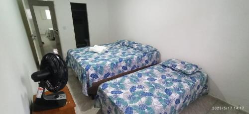 a room with two beds and a chair at Casa no Centro Bananeiras-PB in Bananeiras