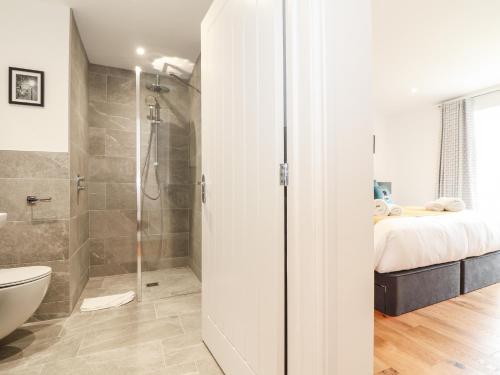 uma casa de banho com um chuveiro, uma cama e um WC. em Trevilges Cottage em Helston