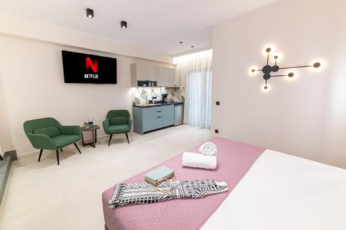 a bedroom with a pink bed and two green chairs at Bella Vasilica Luxury Apartments in Parga