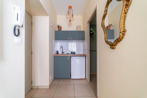 une cuisine avec des armoires bleues et un évier dans un couloir dans l'établissement L'écrin vert luxuriant - Halles & Cathédrale - Une Nuit à Nîmes, à Nîmes