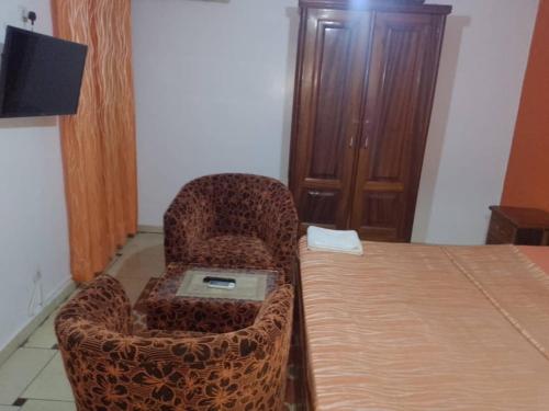 a room with a bed and two chairs with a laptop at Rincon d'Alicia 1 in Dakar