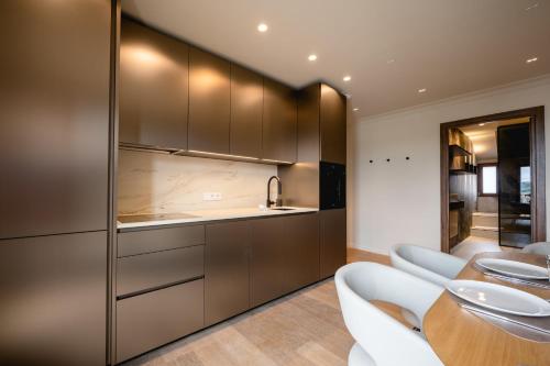 a kitchen with stainless steel cabinets and white chairs at Le Nid du Favre II - Large 2 room with breathtaking view of the lake in Annecy