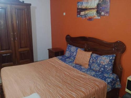 a bedroom with a bed with a wooden headboard at Rincon d'Alicia 1 in Dakar