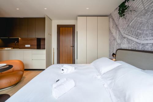 - une chambre avec un lit doté de draps blancs et d'une chaise dans l'établissement Le Nid du Favre I - Charming studio with stunning lake view, à Annecy