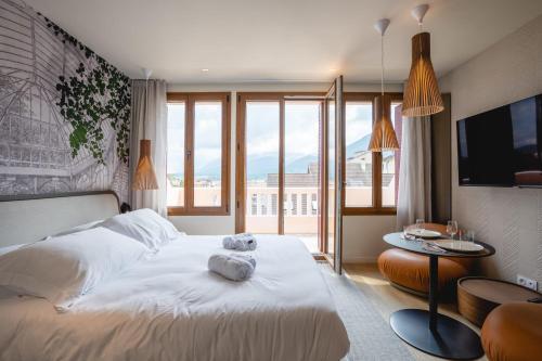 une chambre avec un lit blanc avec une grande fenêtre dans l'établissement Le Nid du Favre I - Charming studio with stunning lake view, à Annecy
