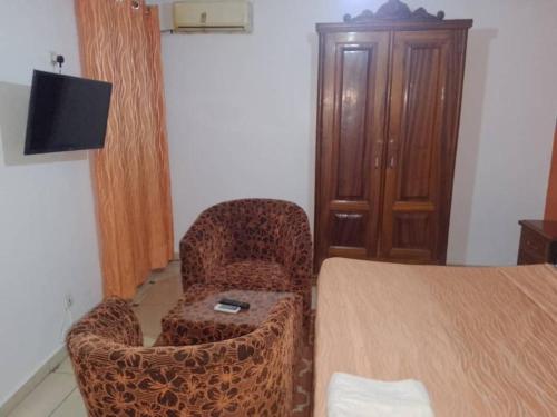 a room with a bed and a chair and a television at Rincon d'Alicia 1 in Dakar