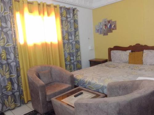 a bedroom with a bed and a chair and a window at Rincon d'Alicia 1 in Dakar