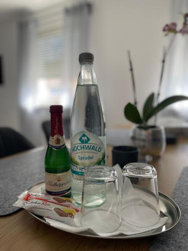 a bottle and two glasses on a plate on a table at Schuhpartment am Pfälzer Wald nähe Outlet Center Zweibrücken in Pirmasens