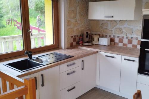 a kitchen with white cabinets and a sink and a window at Maison de montagne vue magnifique in Ventron