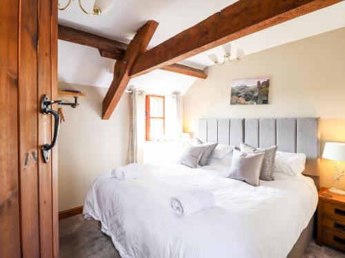 een slaapkamer met een groot wit bed en houten balken bij Beudy Penarddwnion in Dolgellau