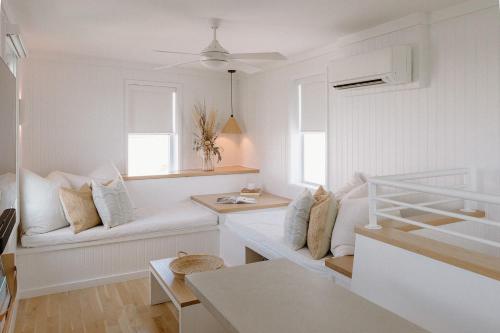 a white living room with a couch and two windows at The Sunsetter by WB Abodes in Wrightsville Beach