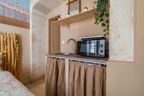 une cuisine avec un micro-ondes et un comptoir avec des rideaux dans l'établissement La Cabane Camarguaise en centre ville - Une Nuit à Nîmes, à Nîmes