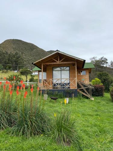 a house in a field with flowers in the grass at Altozano Cabañas in Guatavita