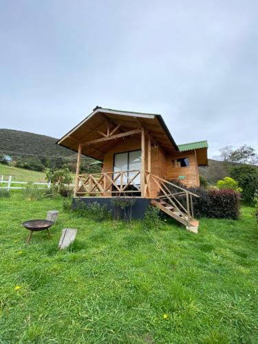 a small wooden house in a field of grass at Altozano Cabañas in Guatavita