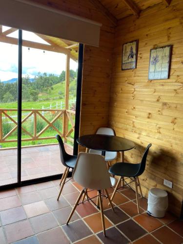 a room with a table and chairs and a balcony at Altozano Cabañas in Guatavita