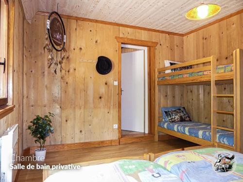 a bedroom with wooden walls and bunk beds at Parc animalier du Hérisson in Doucier