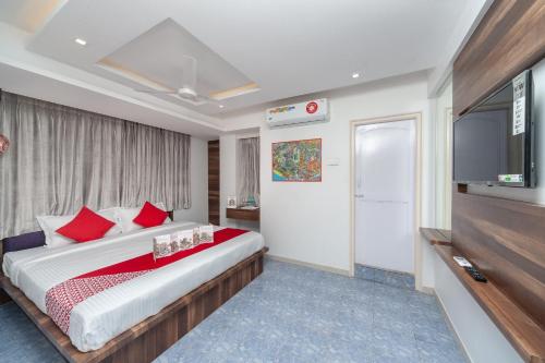 a bedroom with a large bed and a flat screen tv at Capital O Admire Suit Hospitality in Chennai