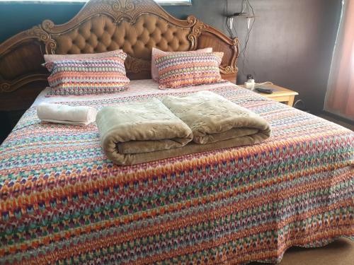 ein Bett mit einer bunten Decke und Kissen darauf in der Unterkunft Randgate guesthouse in Randfontein