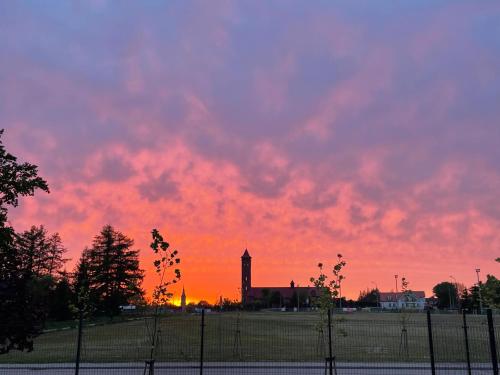 a sunset with a church and a clock tower at Apartamenty Prusa in Mikołajki