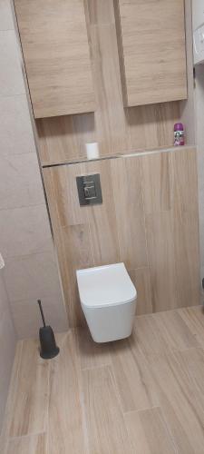 een badkamer met een wit toilet op een houten vloer bij nowy apartament in Ciechocinek