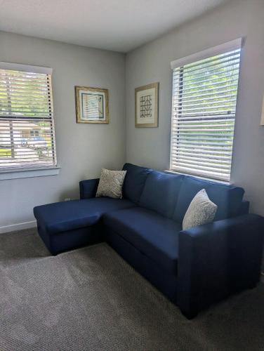 a blue couch in a living room with two windows at Lake ConRoy Estates - Unit A with Pool Access in Montgomery