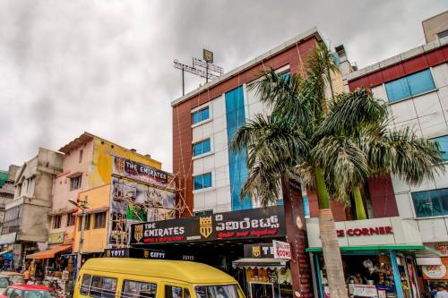 Une camionnette jaune qui descend dans une rue urbaine avec des bâtiments dans l'établissement Capital O 5381 The Emirates Hotel, à Bangalore