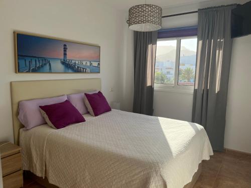 een slaapkamer met een bed met paarse kussens en een raam bij Melo Home Vecindario-Near AirPort-Elevator-Garage in Sardina