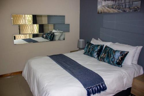 una camera da letto con un grande letto bianco con cuscini di A homely and secure 2 bedroom with uncapped Wifi a Johannesburg