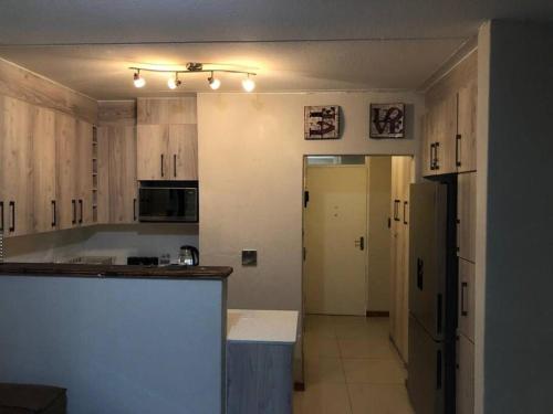 a kitchen with wooden cabinets and a black refrigerator at A homely and secure 2 bedroom with uncapped Wifi in Johannesburg