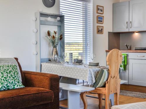 a living room with a table and a chair and a kitchen at Orchard Chalet in Arnhall