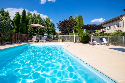 a pool with chairs and umbrellas in a yard at Hôtel Parc Adélie - Logis Hôtels in Montagny-lès-Beaune