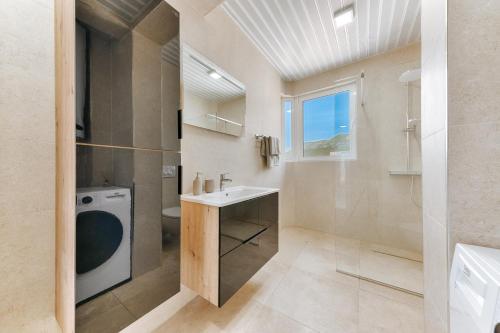 a bathroom with a sink and a washing machine at MonteCasa Seaview Rooms in Dobra Voda