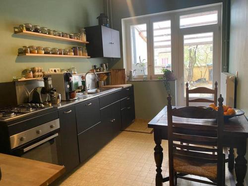 a kitchen with a table and a stove and a window at Superbe appartement avec jardin, sauna et jacuzzi in Brussels