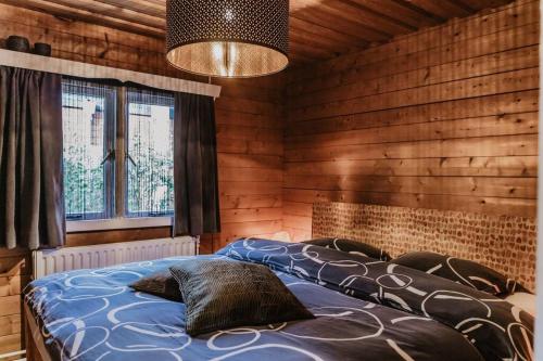a bedroom with a bed in a room with wooden walls at Cosy and Romantic forest house op de Veluwe in Putten